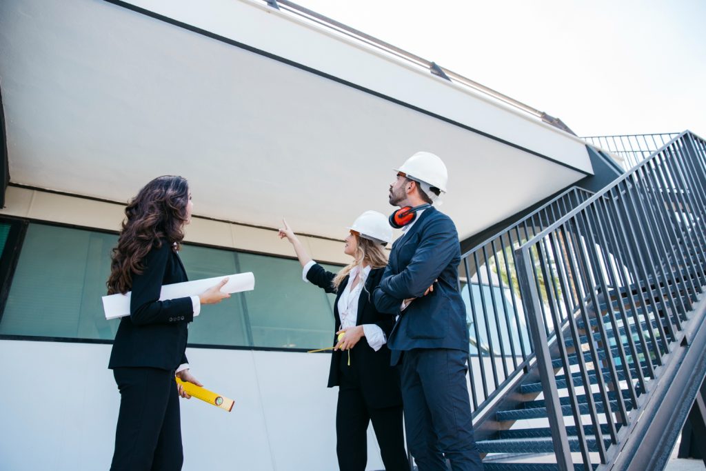 Arquitectos y técnicos con cascos conversando durante una visita de obra