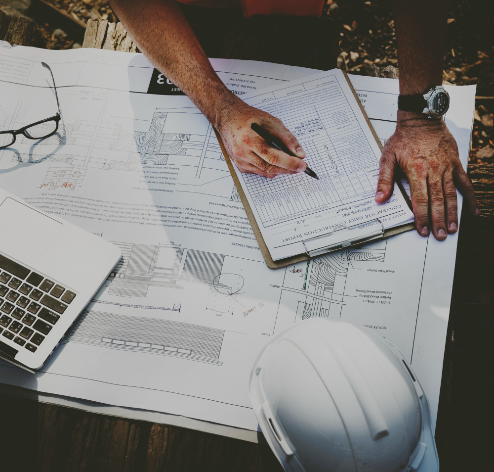 Técnico cumplimentando un informe de evaluación sobre los planos de una obra