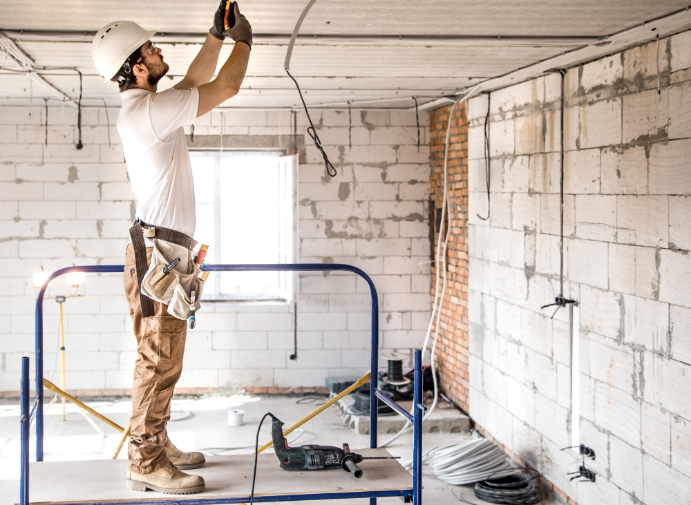 Electricista instalando el cableado del techo en una vivienda en construcción