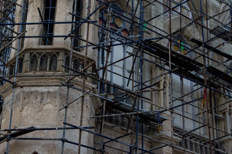 Técnico revisando una pared de ladrillo con patologías en un edificio antiguo