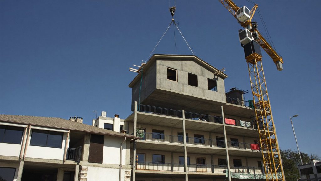 Grúa colocando un módulo prefabricado de hormigón en un edificio residencial en construcción