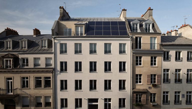 Edificio de viviendas con fachada rehabilitada, ventanas eficientes y paneles solares en cubierta